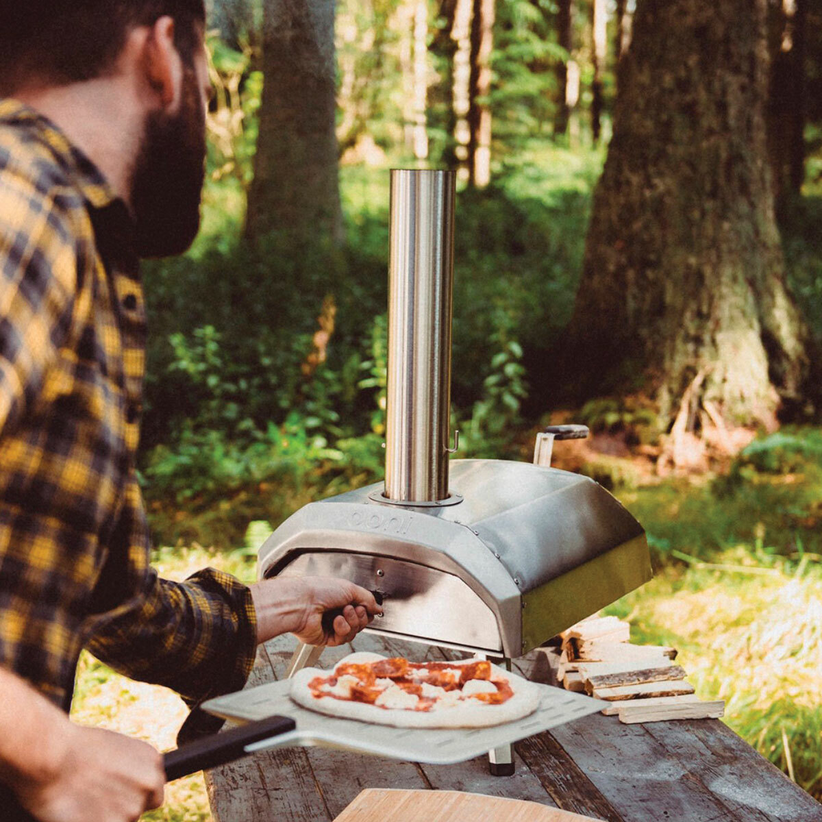 Man putting pizza into an Ooni Karu 12" Pizza Oven