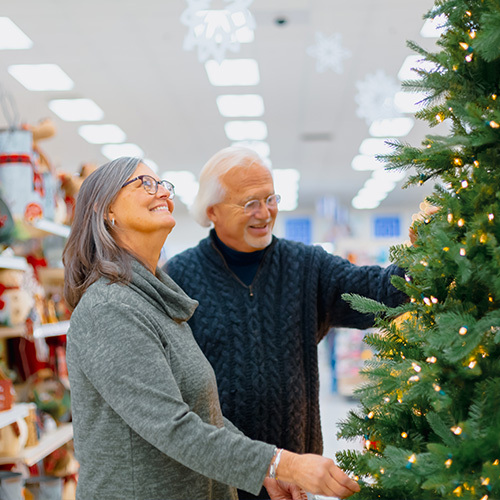 An older couple looks at a Christmas tree.