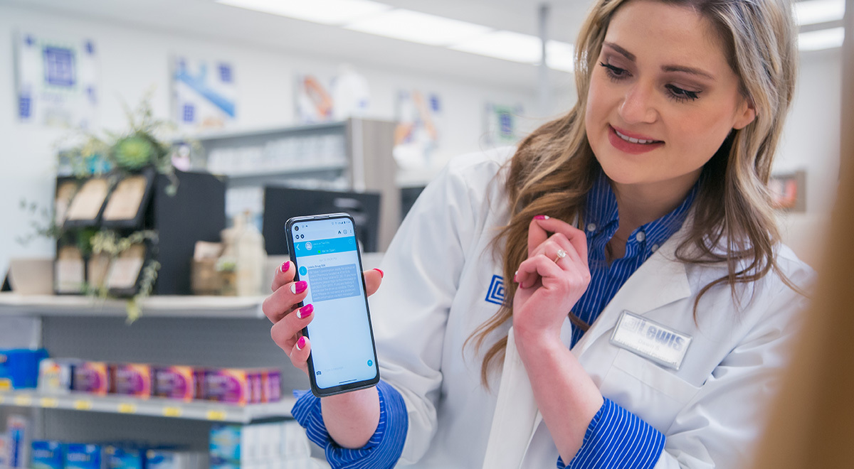 A pharmacist shows a customer how to use the RxLocal app.