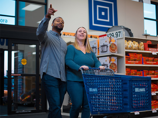 A couple walks into Lewis, pointing and looking at a product.
