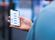 A hand holds a phone with the Lewis App on it.