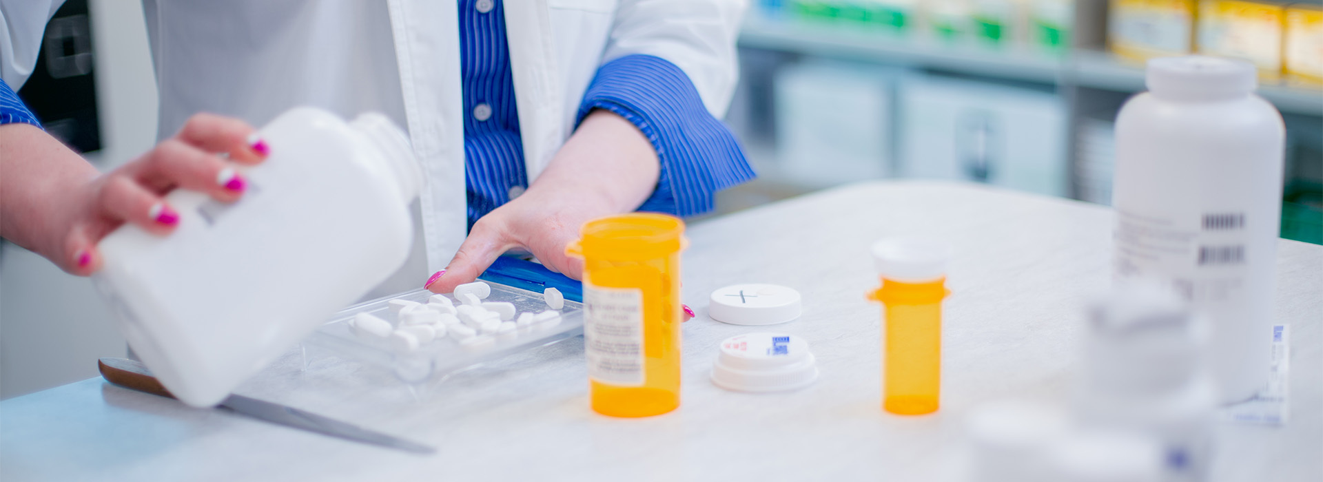 A pharmacist pours pills out into a container.