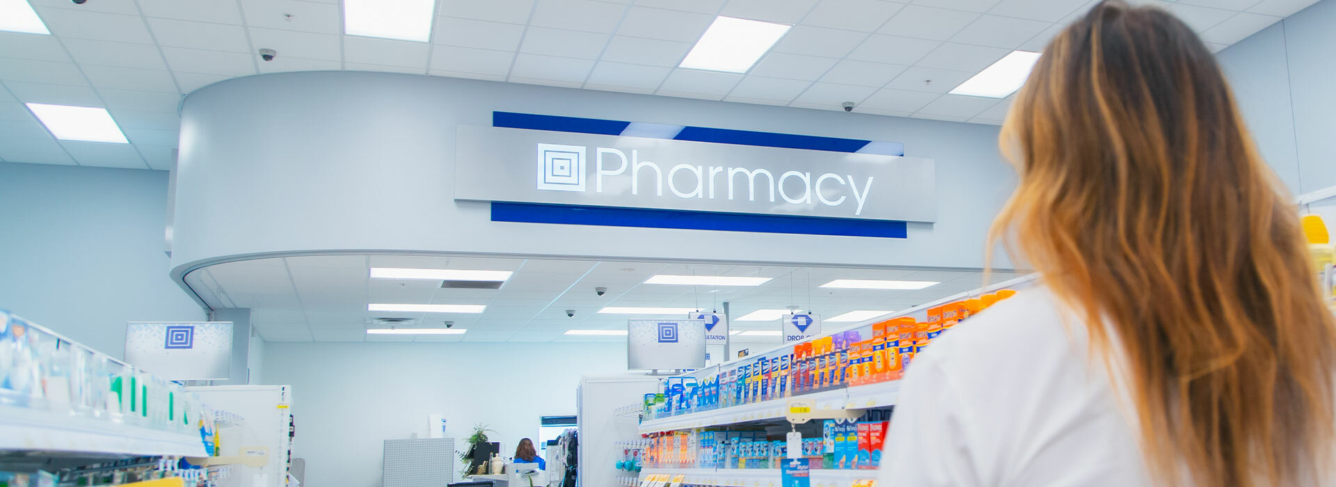 Woman looking up at Pharmacy sign on wall
